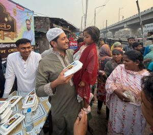 সুবিধাবঞ্চিত এক শিশু মীর ইমরান হোসেন মিথুনের কোলে বসে ইফতার সামগ্রী গ্রহণ করছে।